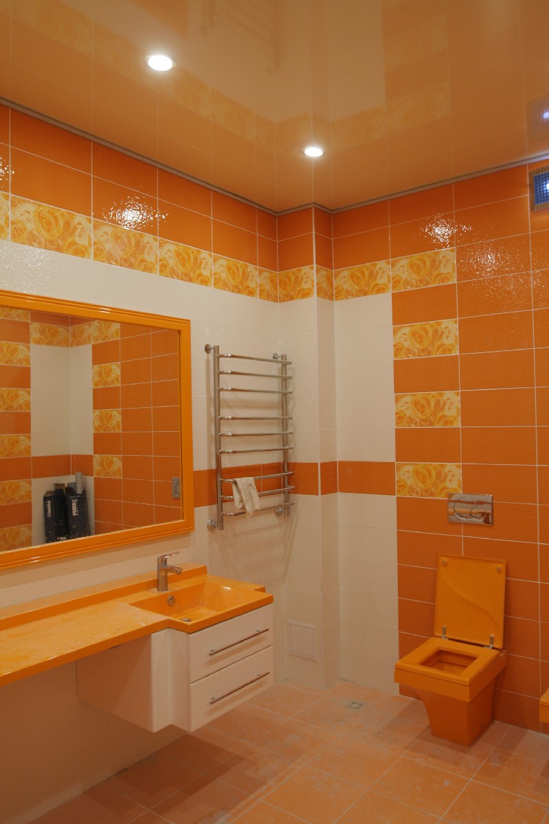 Лаковый оранжевый натяжной потолок в санузле с контурной подсветкой.