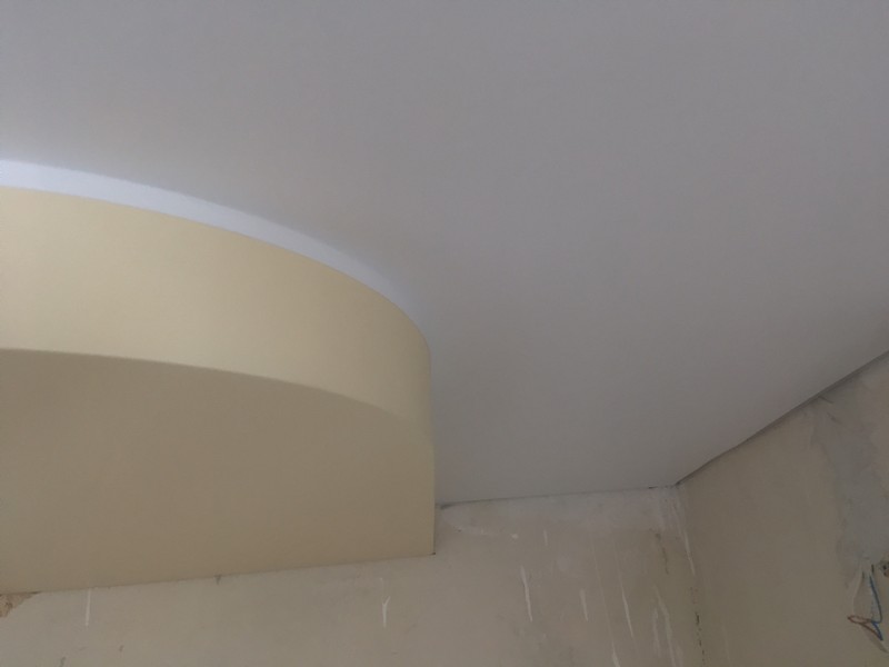 Белая маскировочная лента на стыке двухуровневого натяжного потолка.
